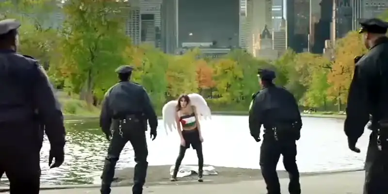 A scene from It Must Be Heaven showing a young girl wearing angel wings and wearing the colours of the Palestinian flag being ambushed by four police officers.