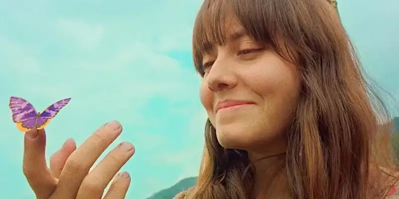 A scene from Luz, The Flower of Evil, showing Laila with a purple butterfly on her finger