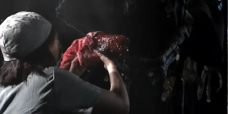 A scene from Mad God where a nurse is holding a new born being up to a demom